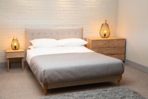 shoreditch upholstered bed with ark bedside & chest of drawers, shoreditch headboard, cage table lamps and mane slate rug.
