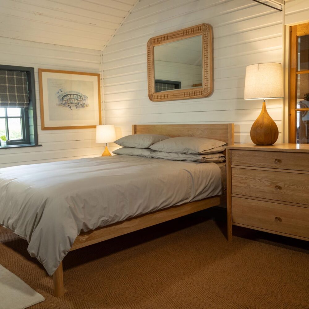 guest bedroom range - oiled oak - guest bed, chest of drawers, bedside table (out of shot) and open wardrobe - shown with cleopatra mirror and bulb lamp bases