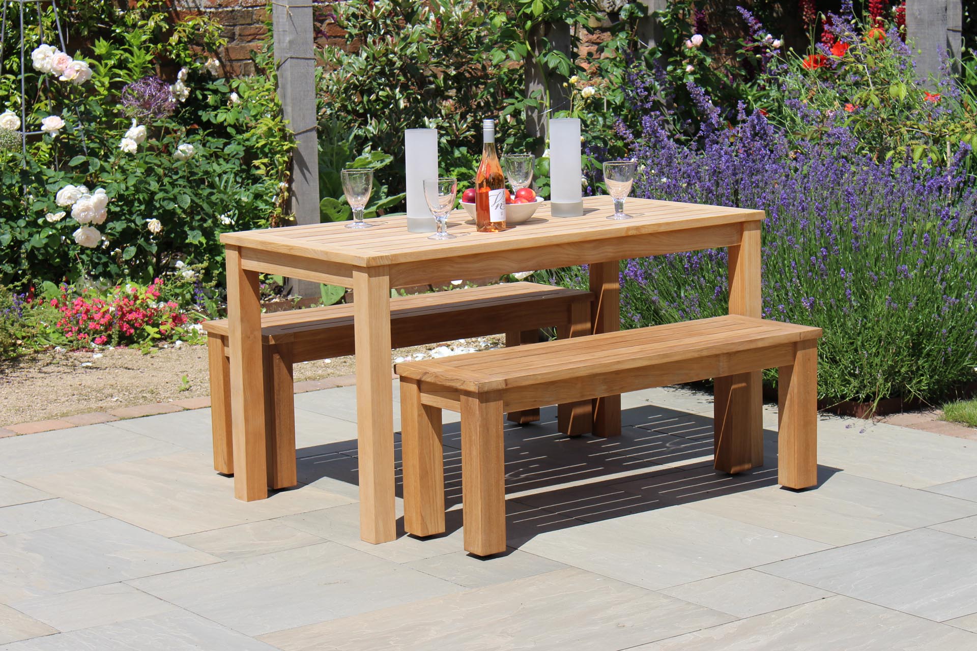 antibes 130cm outdoor table with 116cm outdoor bench - plantation teak. Shown with solstice candleholders.