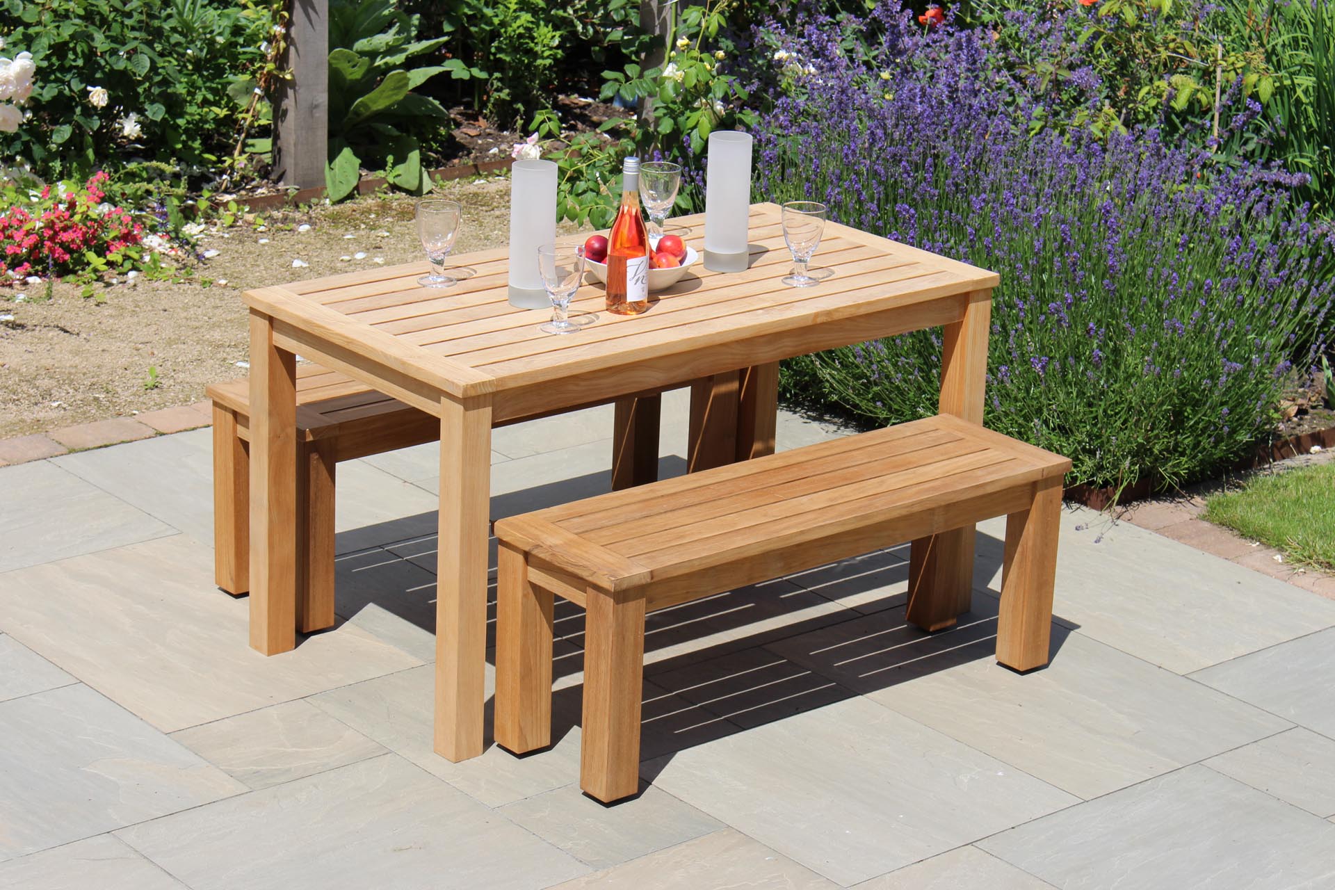 antibes 130cm outdoor table with 116cm outdoor bench - plantation teak. Shown with solstice candleholders.